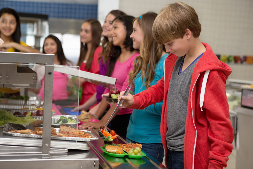 Middle school students choosing healthy food in cafeteria lunch line